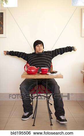 Stock Photograph - Mixed race man stretching at cafe. Fotosearch