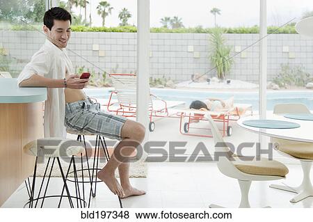 Stock Photo - Mixed race man text messaging on cell phone. Fotosearch