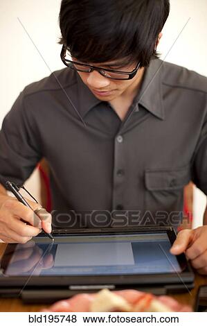 Stock Photo - Mixed race man using digital tablet. Fotosearch