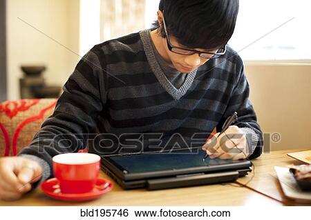 Stock Photograph - Mixed race man writing on digital tablet. Fotosearch
