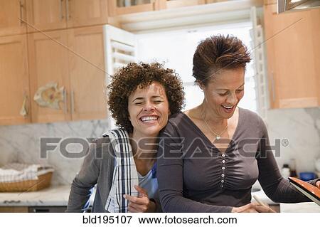 Stock Photo - Mixed race mother and daughter cooking in kitchen. Fotosearch