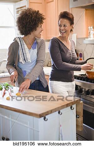 Stock Photograph - Mixed race mother and daughter cooking in kitchen. Fotosearch