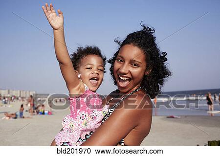 Stock Image - Mixed race mother and daughter enjoying the beach. Fotosearch