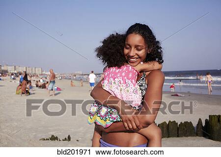 Mixed race mother and daughter hugging at the beach View Large Photo Image Stock Image - Mixed race mother and daughter hugging at the beach. Fotosearch