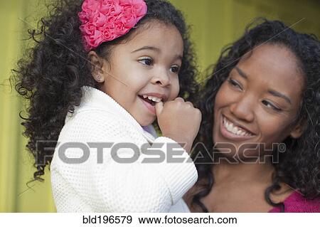 Stock Photo - Mixed race mother and daughter smiling. Fotosearch
