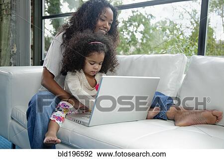 Mixed race mother and daughter using laptop on sofa View Large Photo Image Stock Image - Mixed race mother and daughter using laptop on sofa. Fotosearch