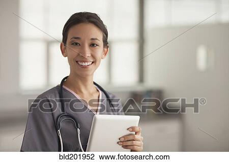 Stock Image - Mixed race nurse holding digital tablet. Fotosearch