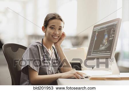 Stock Image - Mixed race nurse using computer. Fotosearch