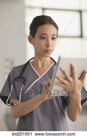 Stock Image - Mixed race nurse using digital tablet. Fotosearch