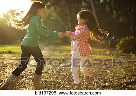 Stock Photo - Mixed race sisters dancing in circle together. Fotosearch