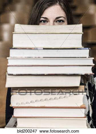 Stock Photo - Mixed race student holding stack of books. Fotosearch