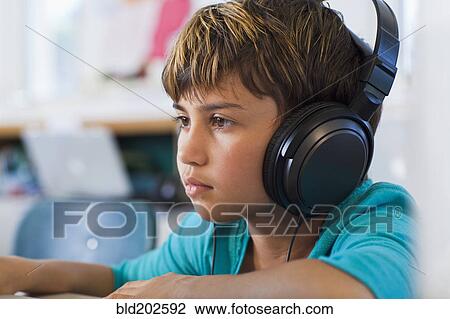 Mixed race student listening to headphones in classroom View Large Photo Image Stock Image - Mixed race student listening to headphones in classroom. Fotosearch