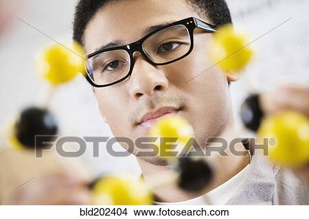 Picture - Mixed race student looking at chemistry model. Fotosearch