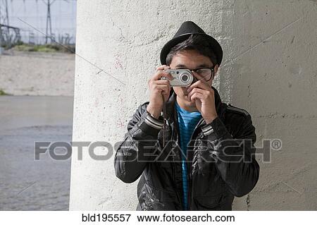 Stock Photo - Mixed race teenage boy taking photograph with digital camera. Fotosearch