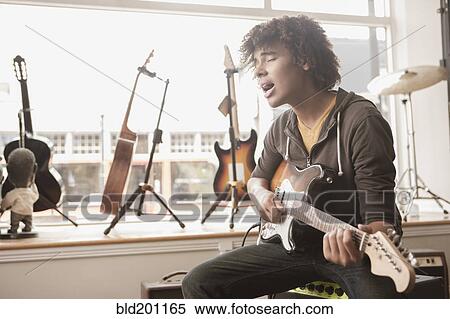 Stock Photography - Mixed race teenager playing electric guitar and singing. Fotosearch