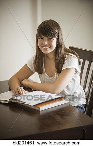 Stock Image - Mixed race woman doing homework. Fotosearch