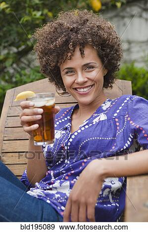 Stock Photo - Mixed race woman drinking iced tea. Fotosearch