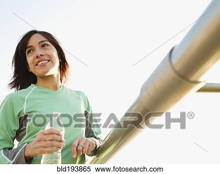 Mixed race woman drinking water by railing View Large Photo Image Stock Photography - Mixed race woman drinking water by railing. Fotosearch