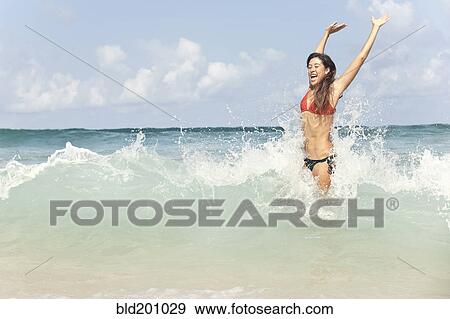 Stock Photo - Mixed race woman enjoying ocean waves. Fotosearch