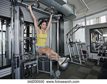 Stock Image - Mixed race woman exercising in health club. Fotosearch