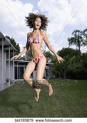 Mixed race woman in bikini jumping in backyard View Large Photo Image Stock Photo - Mixed race woman in bikini jumping in backyard. Fotosearch