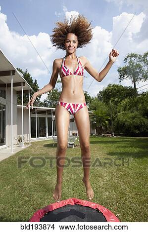 Picture - Mixed race woman jumping on mini-tram in backyard. Fotosearch
