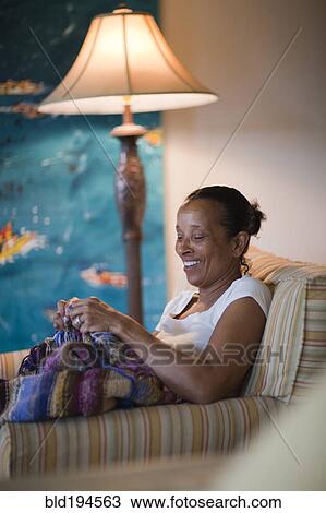 Stock Image - Mixed race woman knitting blanket. Fotosearch