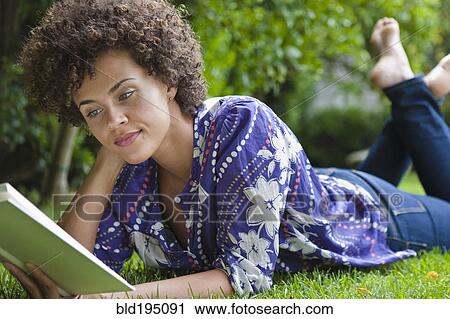 Mixed race woman laying in grass reading book View Large Photo Image Stock Image - Mixed race woman laying in grass reading book. Fotosearch