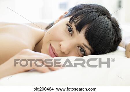 Picture - Mixed race woman laying on bed. Fotosearch