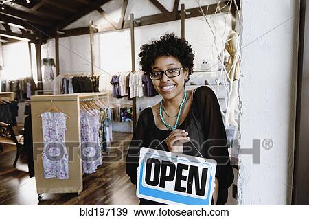 Mixed race woman putting open sign on door View Large Photo Image Stock Photo - Mixed race woman putting open sign on door. Fotosearch