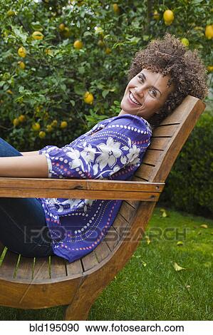 Stock Image - Mixed race woman relaxing in backyard. Fotosearch