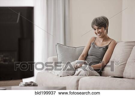 Stock Photo - Mixed race woman relaxing on sofa. Fotosearch