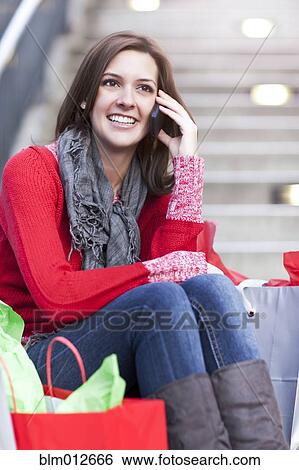Stock Photograph - Mixed race woman shopping and talking on cell phone. Fotosearch