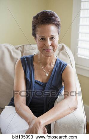 Stock Image - Mixed race woman sitting in armchair. Fotosearch