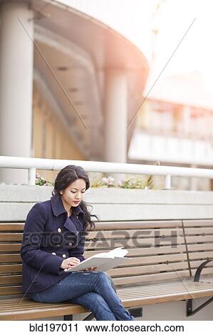 Mixed race woman sitting on bench reading View Large Photo Image Stock Image - Mixed race woman sitting on bench reading. Fotosearch