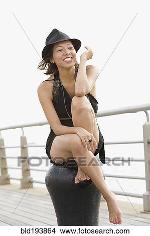 Picture - Mixed race woman sitting on pier. Fotosearch