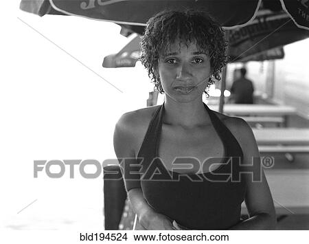Picture - Mixed race woman sitting under umbrella in cafe. Fotosearch