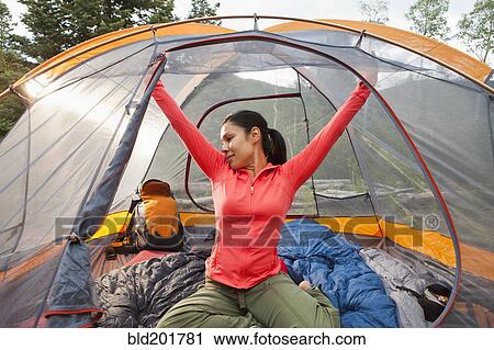 Stock Image - Mixed race woman stretching in tent. Fotosearch