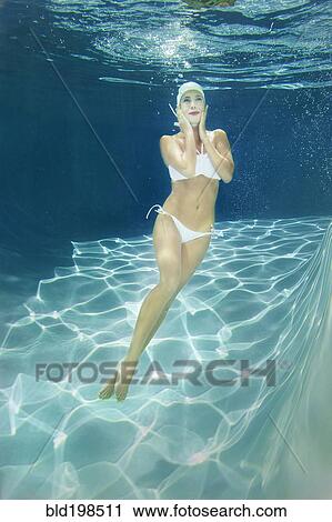 Stock Image - Mixed race woman swimming underwater. Fotosearch