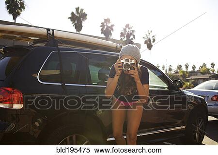 Stock Photography - Mixed race woman taking photograph with retro camera. Fotosearch