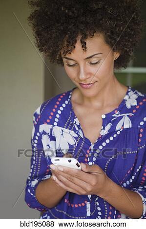 Stock Photo - Mixed race woman text messaging on cell phone. Fotosearch
