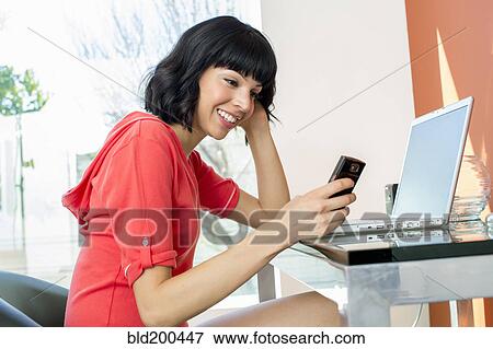 Stock Photo - Mixed race woman text messaging on cell phone. Fotosearch