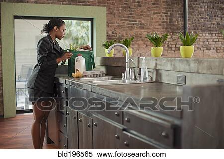 Mixed race woman unloading groceries in kitchen View Large Photo Image Stock Photography - Mixed race woman unloading groceries in kitchen. Fotosearch
