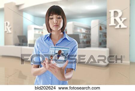 Picture - Mixed race woman using digital tablet in pharmacy. Fotosearch