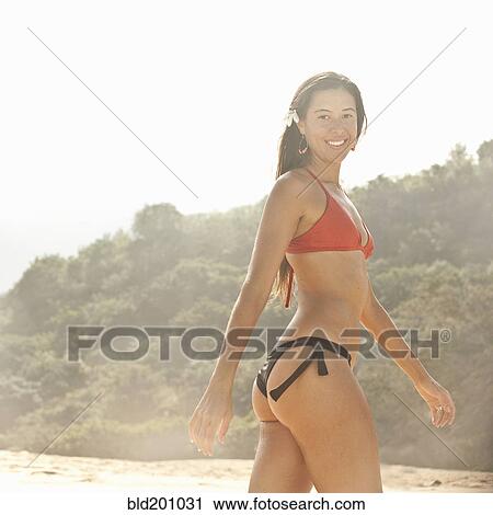 Stock Image - Mixed race woman walking on beach. Fotosearch