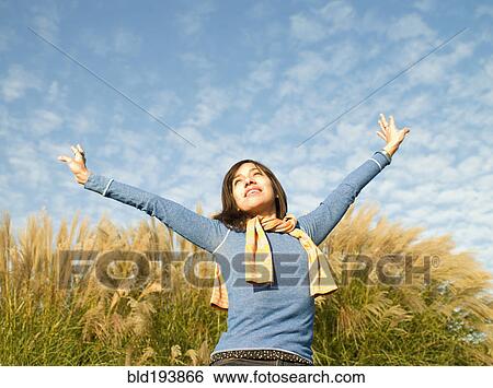 Stock Photograph - Mixed race woman with arms outstretched outdoors. Fotosearch
