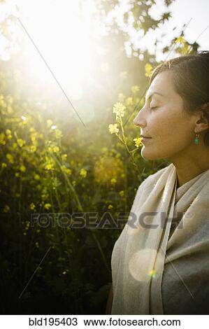 Stock Image - Mixed race woman with eyes closed in field. Fotosearch