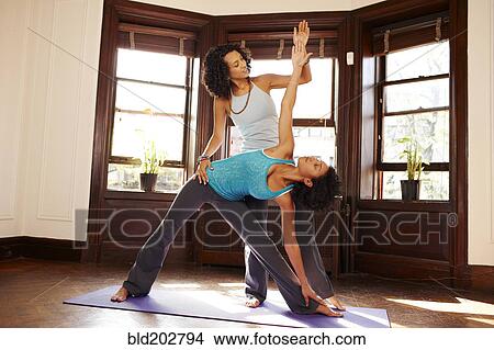 Picture - Mixed race women practicing yoga in living room. Fotosearch