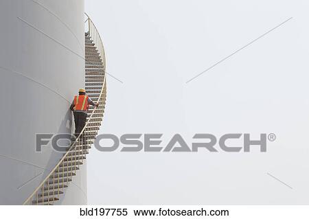 Mixed race worker climbing staircase on storage tank View Large Photo Image Stock Photography - Mixed race worker climbing staircase on storage tank. Fotosearch