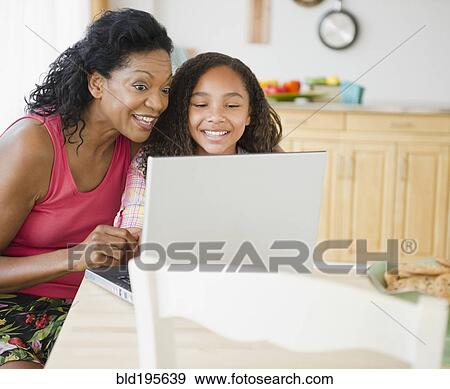Stock Photo - Mother and daughter looking at laptop. Fotosearch